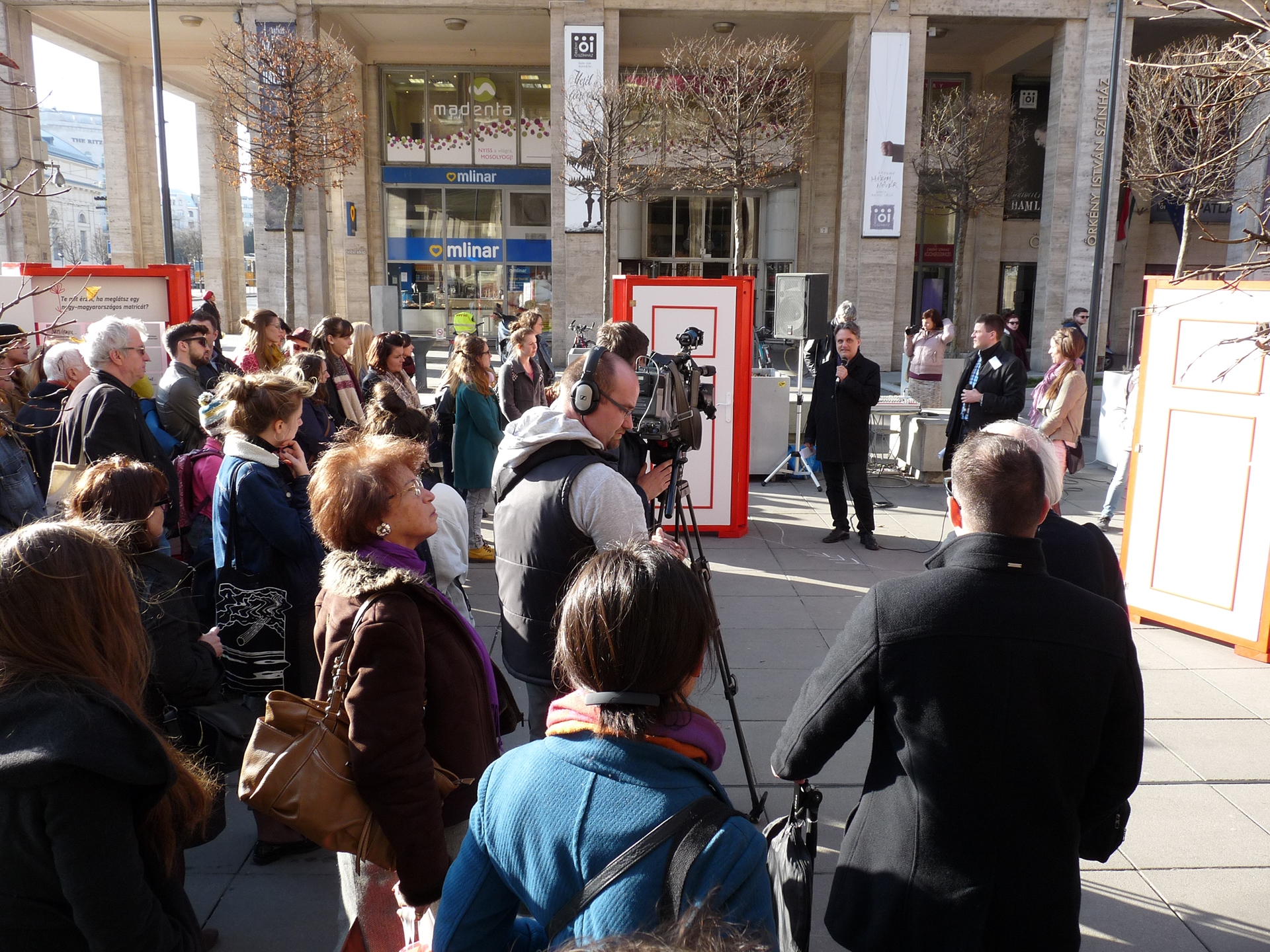 visitors and the media looking at the man opening the exhibition in the middle of the square